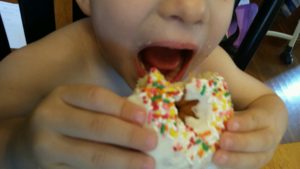 boy eating chocolate cake donut he loves with sprinkle for breakfast, lunch, and dinner